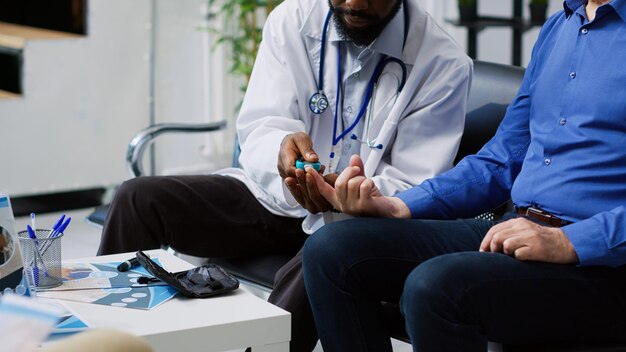 Un médico está sentado con un paciente y un médico está comprobando el color azul de la mano.