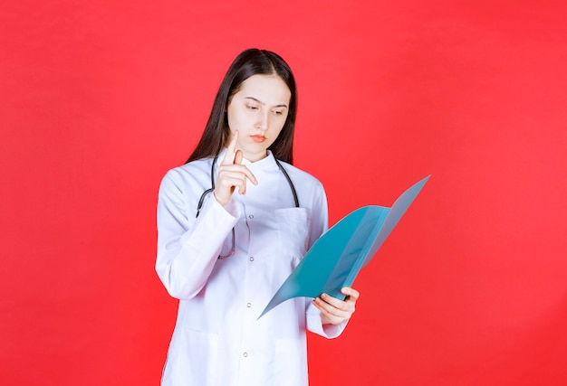 Médico con un estetoscopio sosteniendo la historia del paciente, leyéndolo y poniéndose nervioso.