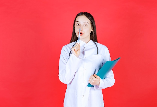 Médico con un estetoscopio sosteniendo la historia del paciente y pidiendo silencio.