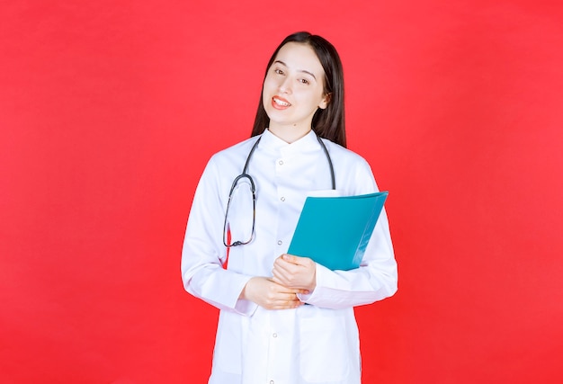 Médico con un estetoscopio sosteniendo la historia del paciente.