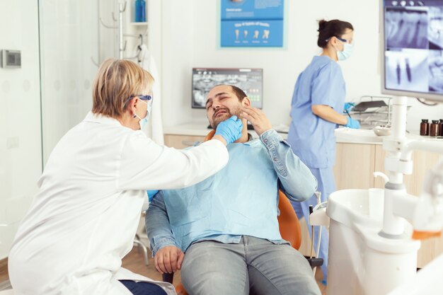 Médico estomatólogo que controla el dolor de dientes del paciente durante la cita de estomatología