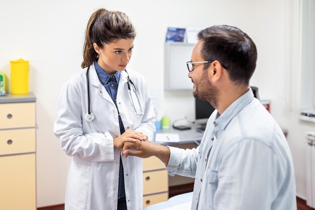 Médico experimentado discutiendo con el paciente su expediente médico privado Joven consultando con su médico y consultando sobre la forma de su tratamiento médico y seguro médico