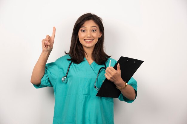 Médico feliz con estetoscopio sosteniendo portapapeles sobre fondo blanco. Foto de alta calidad