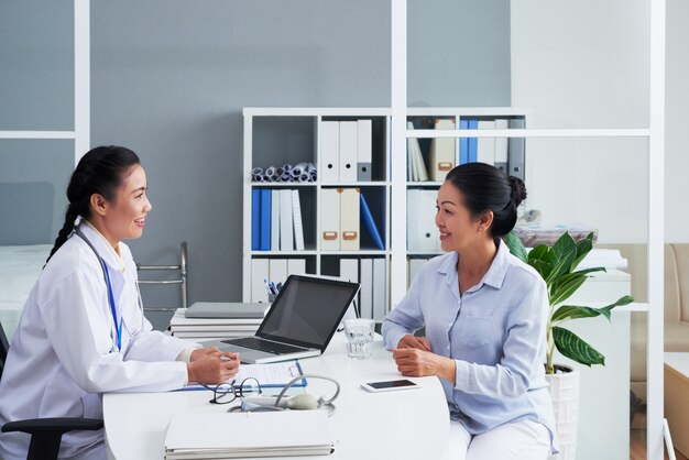 Médico femenino asiático consultar a mujer en oficina