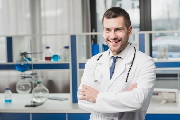 Médico guapo sonriente con los brazos cruzados