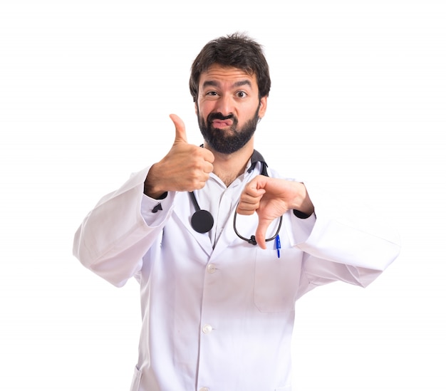 Médico haciendo un signo bueno-malo sobre fondo blanco