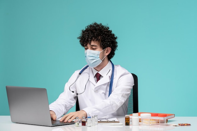 Médico joven y apuesto que trabaja en una computadora de forma remota en una bata de laboratorio escribiendo