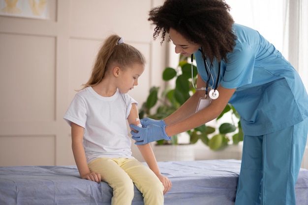 Médico joven asegurándose de que una niña esté bien después de la vacunación