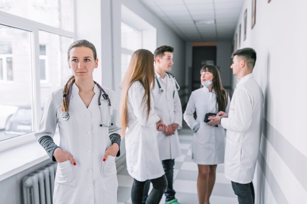 Médico joven de pie en el pasillo con colegas