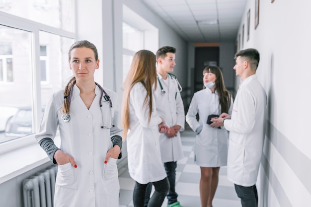 Médico joven de pie en el pasillo con colegas