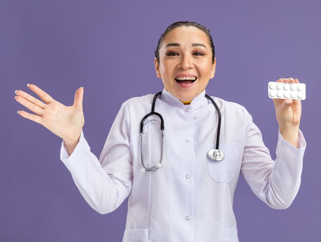 Médico joven sosteniendo blister con pastillas feliz y emocionado