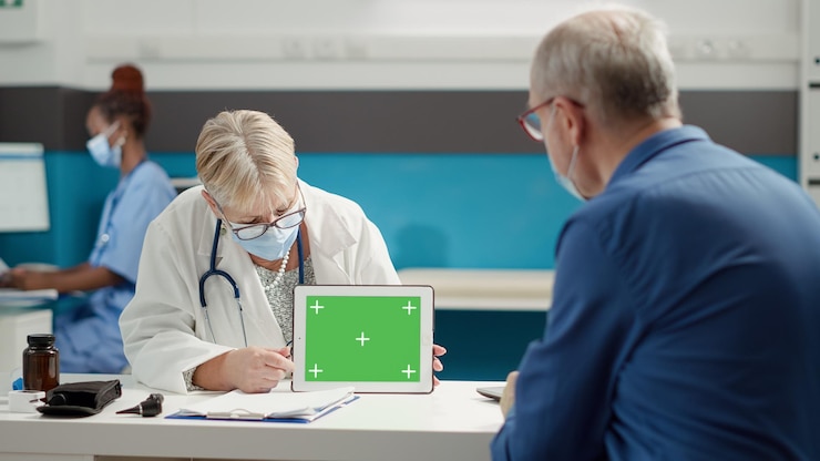 Foto gratuito médico y jubilado mirando la pantalla verde en la tableta durante la pandemia de covid 19 en el gabinete médico. fondo de maqueta en blanco con copyspace aislado y plantilla de clave de croma.