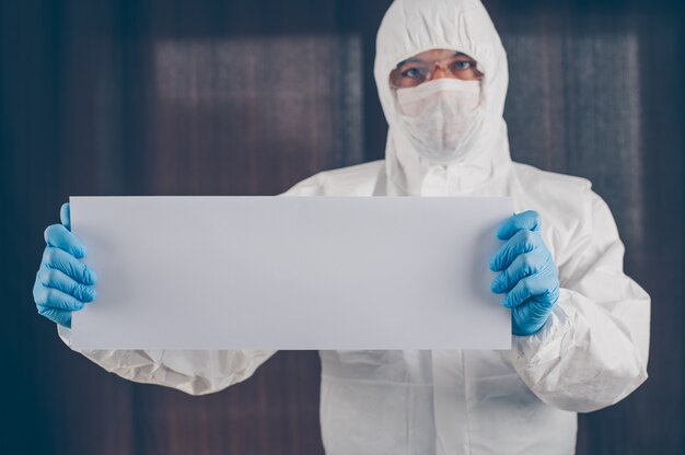 Un médico en máscara, guantes y traje protector con papel blanco