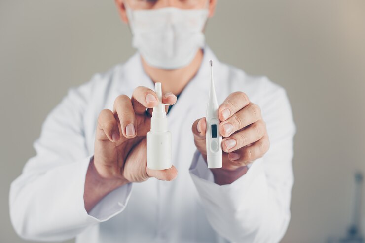 Foto gratuito un médico con máscara con termómetro y spray nasal en sus manos. vista lateral.