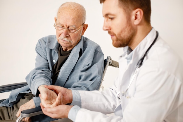 Médico masculino y anciano en silla de ruedas aislado en un fondo blanco