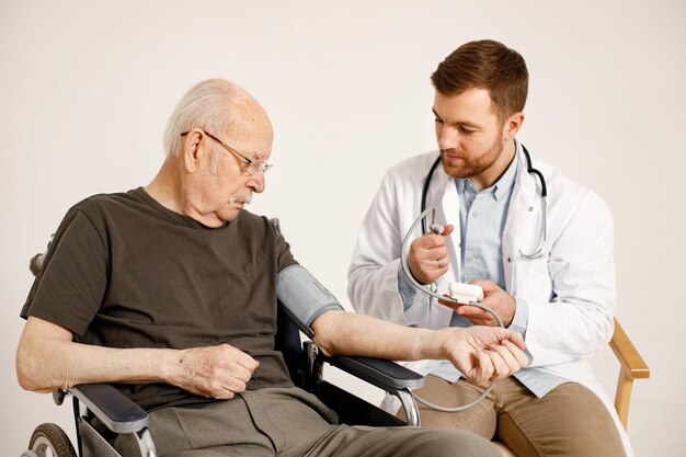 Médico masculino y anciano en silla de ruedas aislado en un fondo blanco