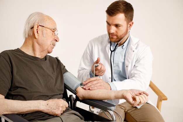 Médico masculino y anciano en silla de ruedas aislado en un fondo blanco