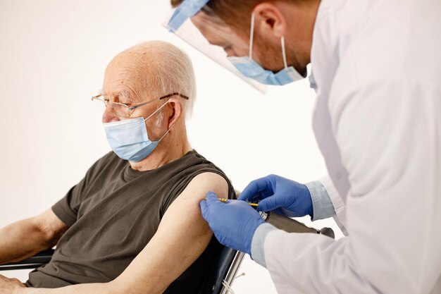 Médico masculino y anciano en silla de ruedas aislado en un fondo blanco