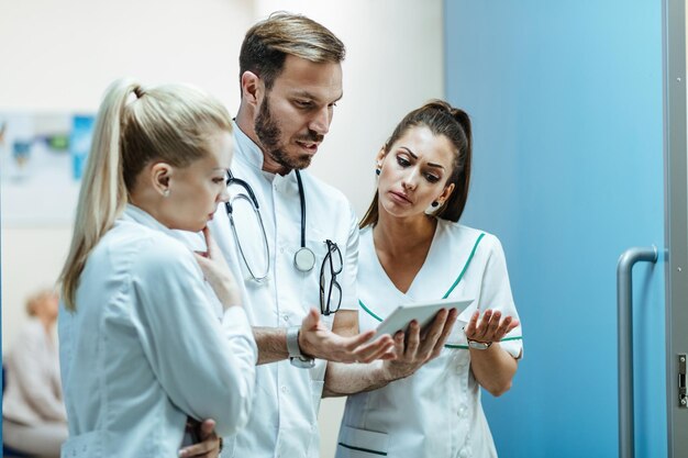 Médico masculino y enfermeras comunicándose mientras trabajan en una tableta digital en la clínica