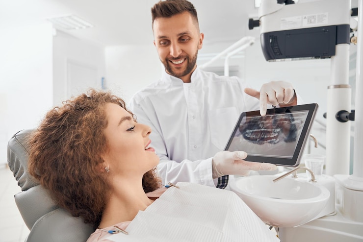Médico masculino que muestra imágenes de rayos X de los dientes en la tableta