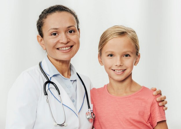 Médico y niña sonriente de tiro medio posando