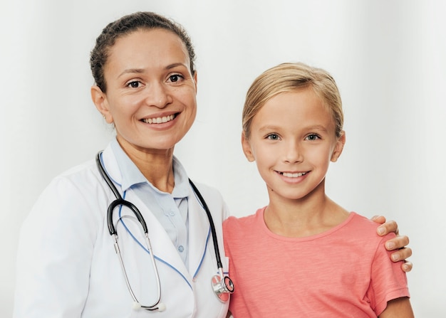 Médico y niña sonriente de tiro medio posando