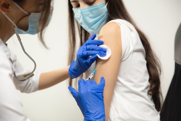 Médico o enfermera que administra la vacuna al paciente con la jeringa inyectada en el hospital. Preparando dosis en aguja. Protección contra coronavirus, pandemia COVID-19 y neumonía. Salud, medicina.