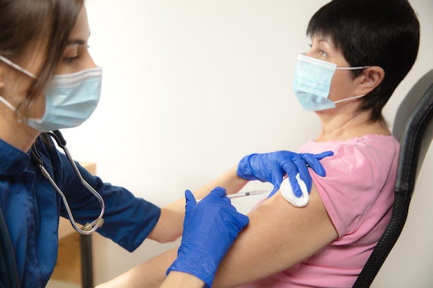 Médico o enfermera que administra la vacuna al paciente con la jeringa inyectada en el hospital. Preparando dosis en aguja. Protección contra coronavirus, pandemia COVID-19 y neumonía. Salud, medicina.