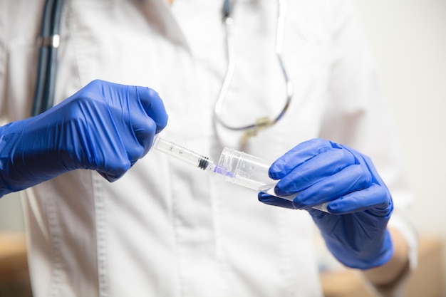 Médico o enfermera que administra la vacuna al paciente usando la jeringa inyectada en el hospital. Preparación de dosis en aguja. Protección contra el coronavirus, la pandemia de COVID-19 y la neumonía. Salud, medicina.