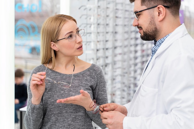 Foto gratuita médico óptico en la tienda con el cliente.