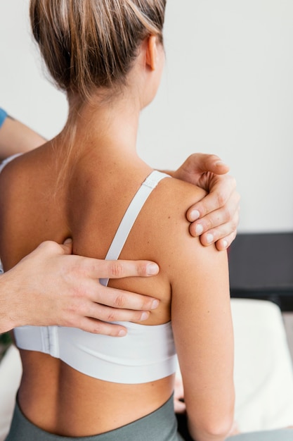 Foto gratuita médico osteópata masculino comprobando la escápula del paciente femenino