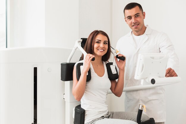 Médico y paciente femenino posando junto a la máquina médica