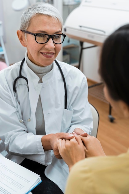 Médico y paciente tomados de la mano después de buenas noticias