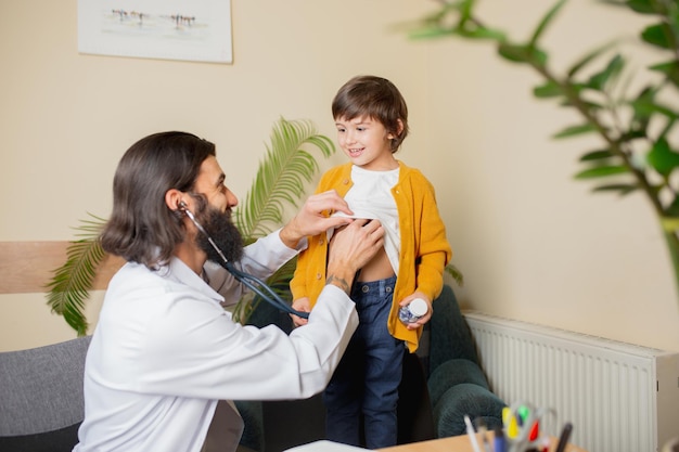 Médico pediatra examinando a un niño en el consultorio médico comfortabe