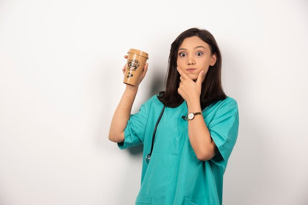 Médico positivo con estetoscopio sosteniendo la taza sobre fondo blanco.