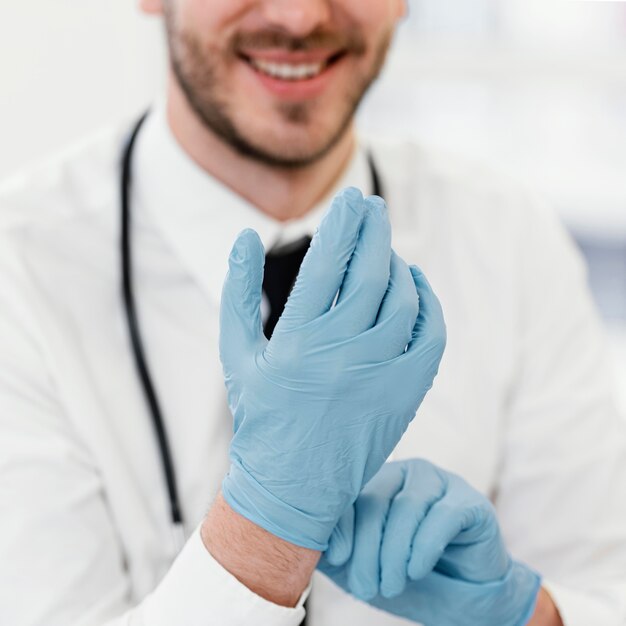 Médico de primer plano poniéndose guantes