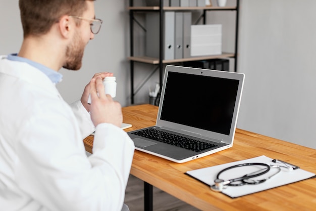 Médico de primer plano trabajando con ordenador portátil