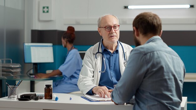 Médico principal que realiza consultas de atención médica con adultos jóvenes, habla sobre el diagnóstico de enfermedades y el tratamiento de recuperación en el consultorio. Hablar sobre analgésicos y medicamentos para enfermedades.