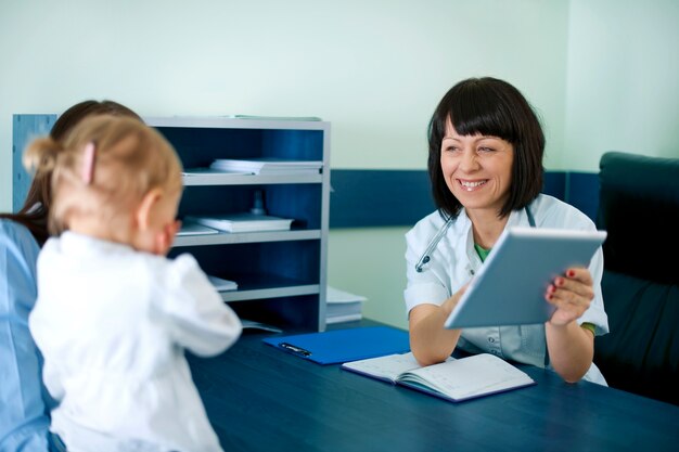 Médico que muestra los resultados médicos de la madre en la tableta