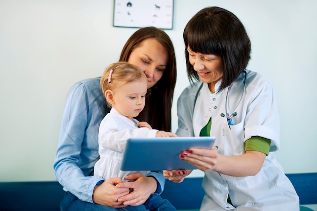 Médico que muestra los resultados médicos de la madre en la tableta