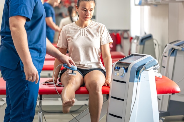 Foto gratuita médico que utiliza una máquina para tratar las articulaciones de la rodilla de un paciente