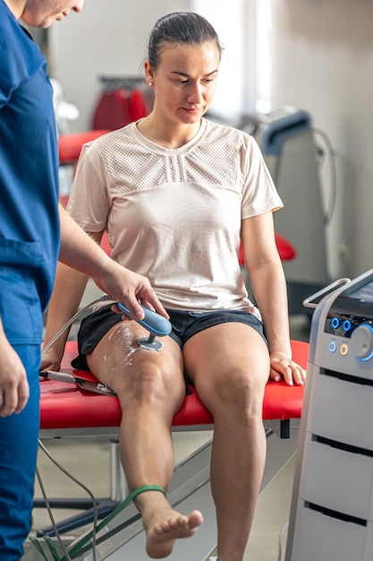 Foto gratuita médico que utiliza una máquina para tratar las articulaciones de la rodilla de un paciente