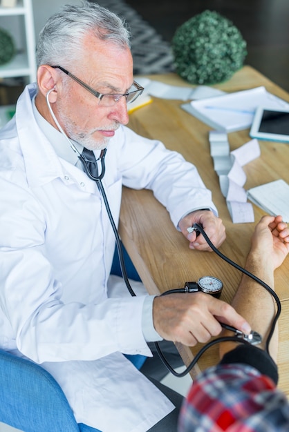 Foto gratuita médico serio medir la presión arterial del paciente