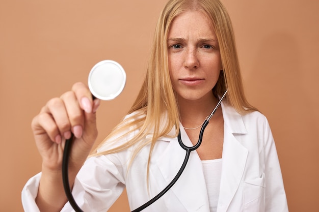 Médico de sexo femenino joven con el pelo rubio recto con estetoscopio