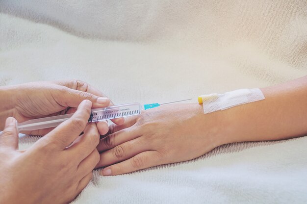 Médico sosteniendo la jeringa en la mano inyecta a un brazo paciente