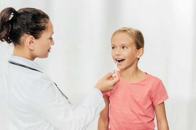 Médico de tiro medio controlando la temperatura de la niña