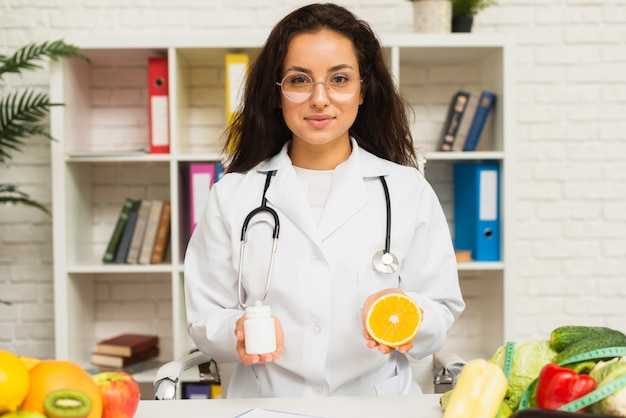 Médico de tiro medio con estetoscopio y naranja