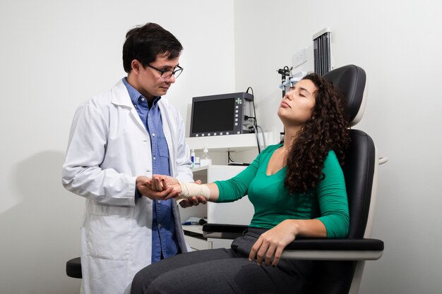 Médico de tiro medio examinando el brazo vendado