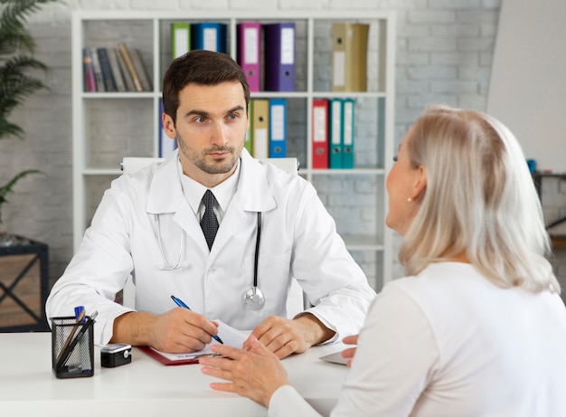 Foto gratuita médico de tiro medio hablando con mujer