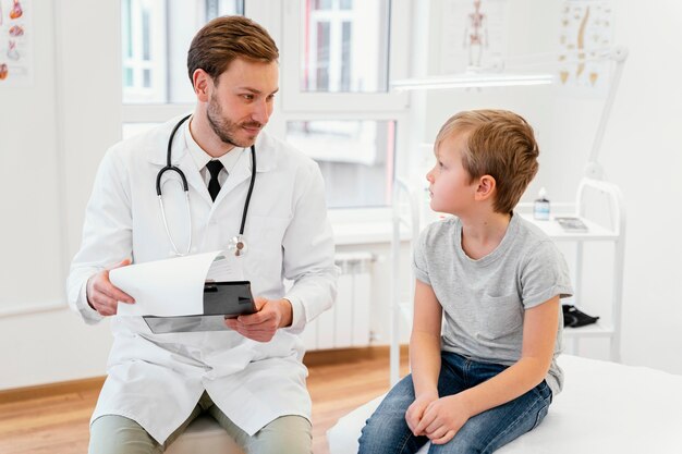 Médico de tiro medio hablando con niño